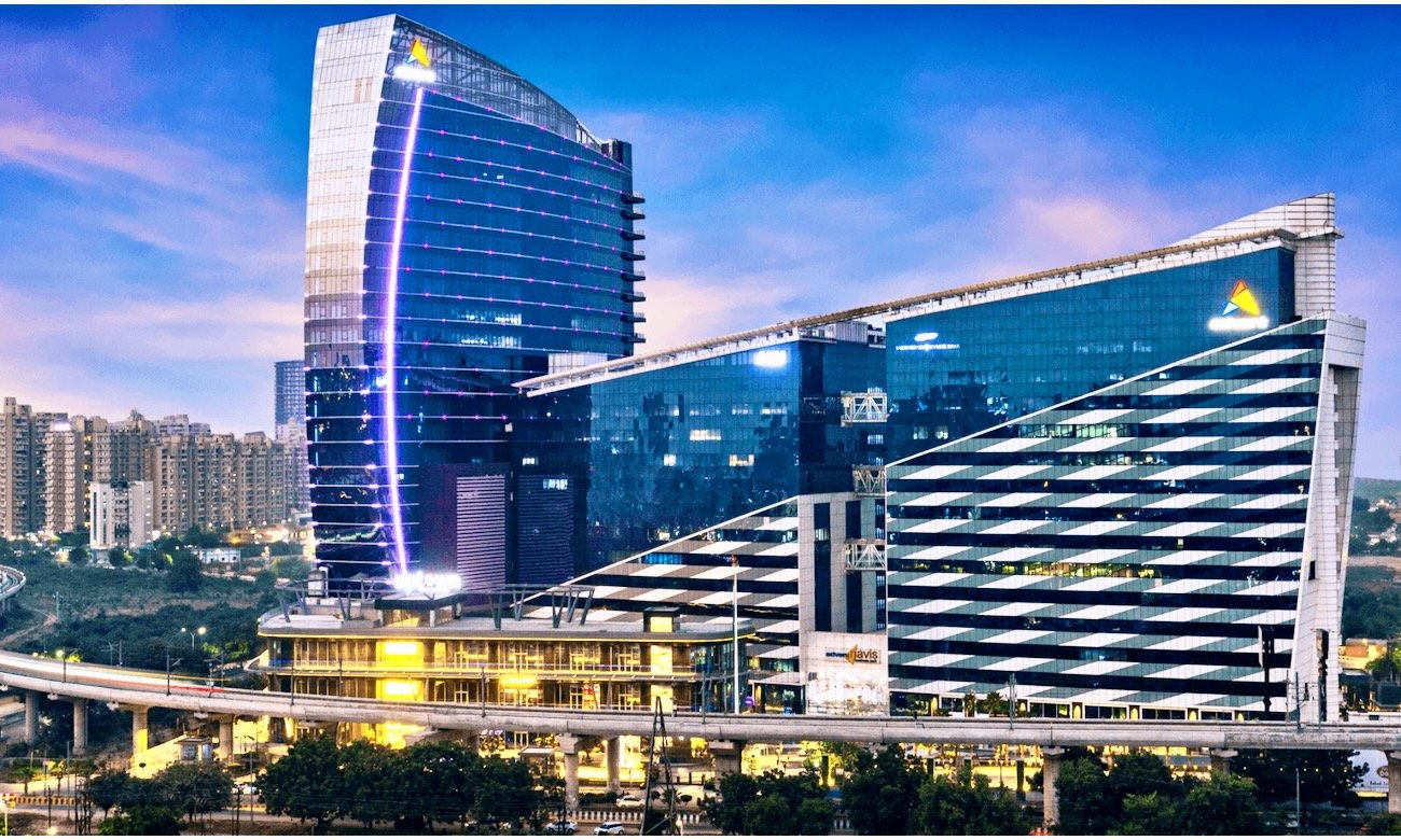A wide, clean expressway in Noida with modern buildings alongside